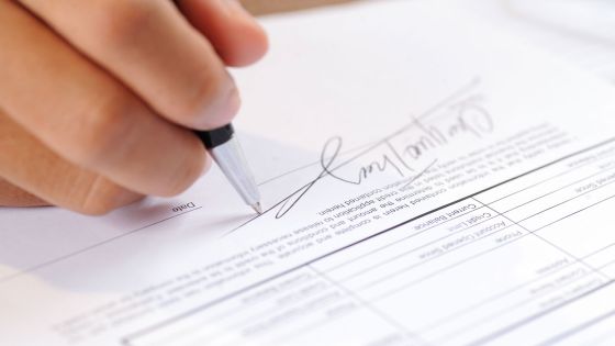 Un personne, qui tient un crayon, signe un contrat