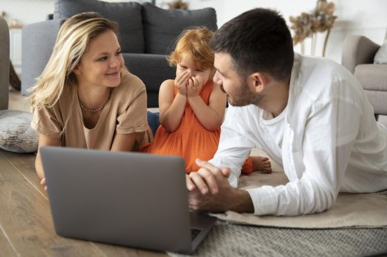 Un couple de parents et leur petite fille sont devant un ordinateur portable