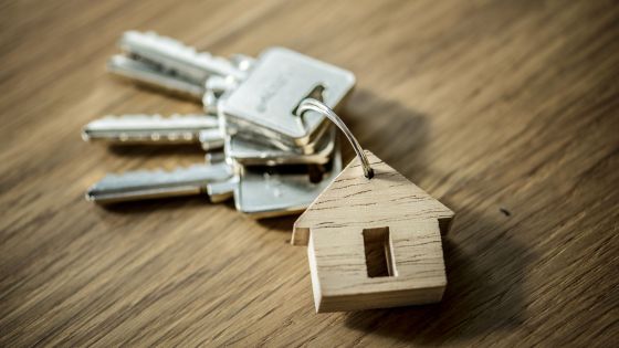 Des clés, avec un porte-clé d'une petite maison en bois, sont sur une table en bois.