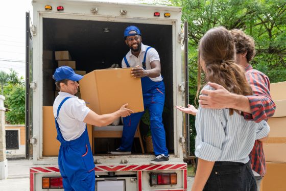 Un déménageur en uniforme bleu décharge des cartons d'un camion.