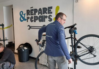 Photo d'un homme en train de réparer un vélo dans le cadre de l'atelier Répars et Répare Coulaines