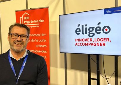 Cyril RAFFIER se tient devant un écran sur lequel figure le logo d'éligéo en grand.