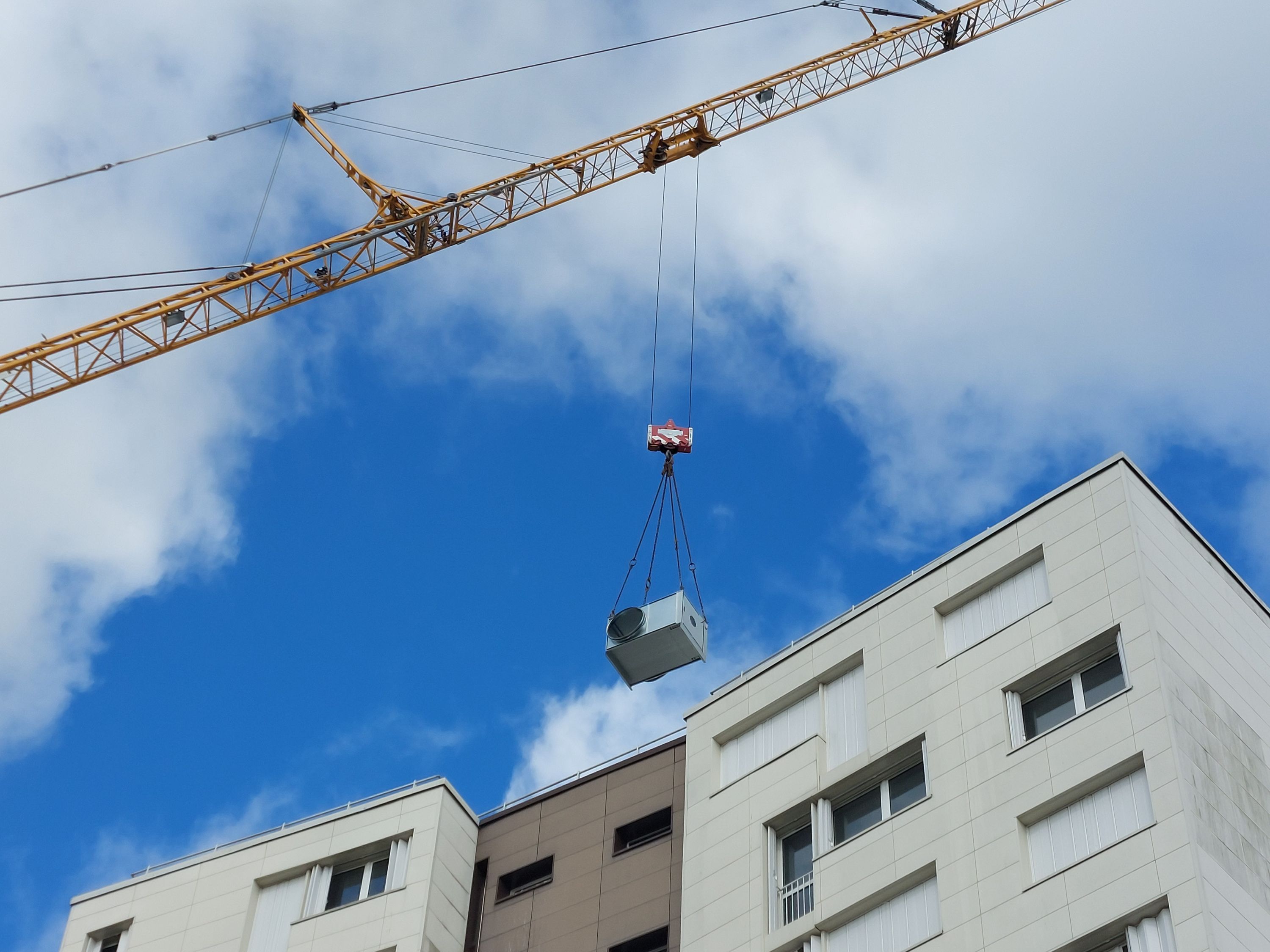 Grue qui monte un bloc de VMC sur une tour